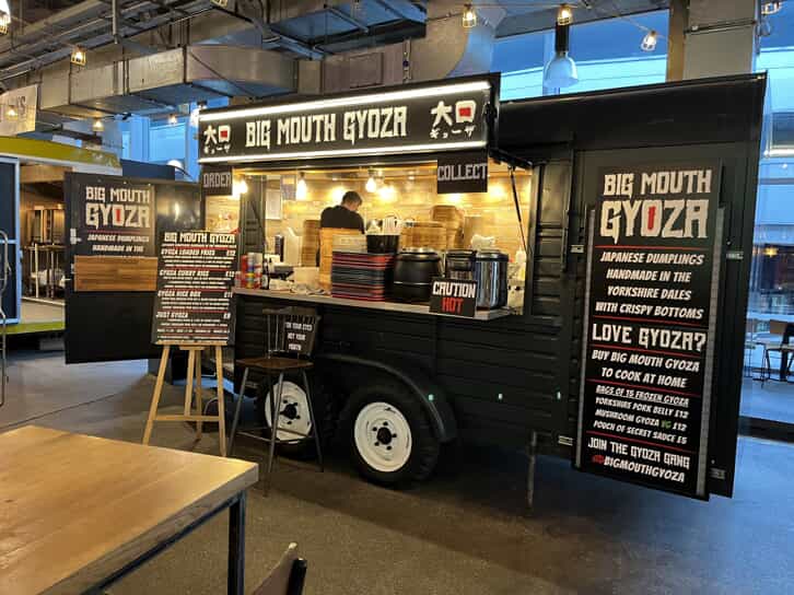 a food truck with signs for big mouth gyoza and menu boards